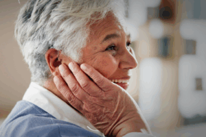 A woman holds her ear and smiles.