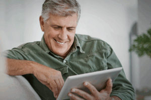 A man smiles as he reads helpful info on his tablet.