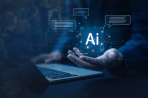 Human hand hovers over a laptop with “AI” animations.